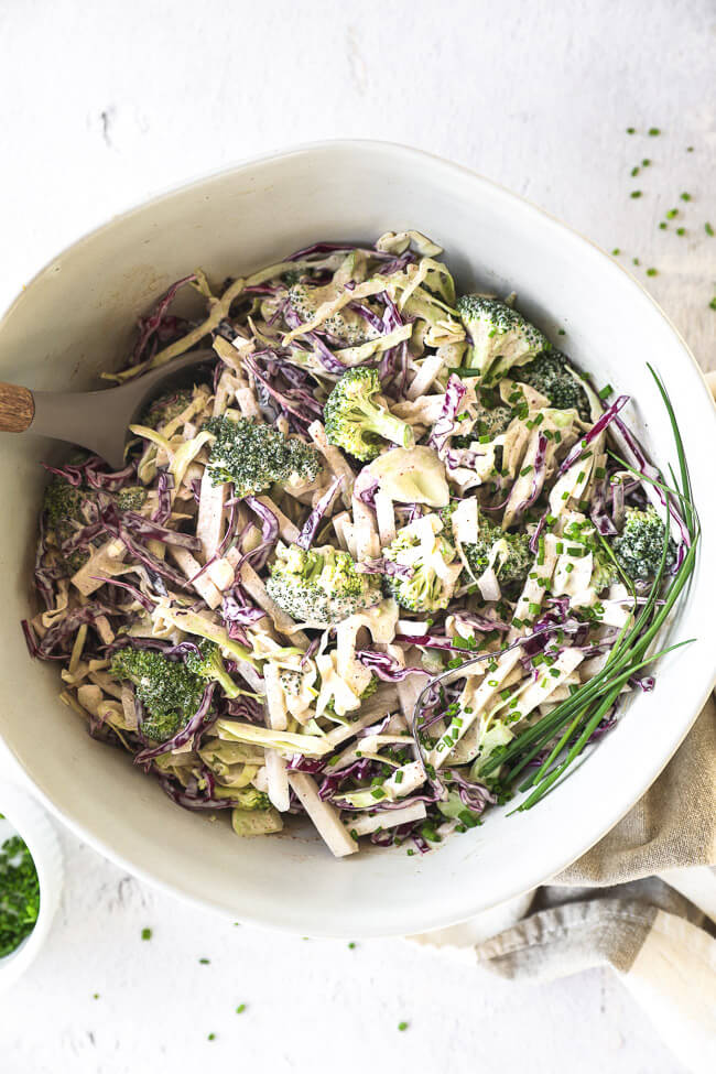 Overhead image of rich and creamy keto coleslaw all mixed up in a large serving bowl with a spoon. 