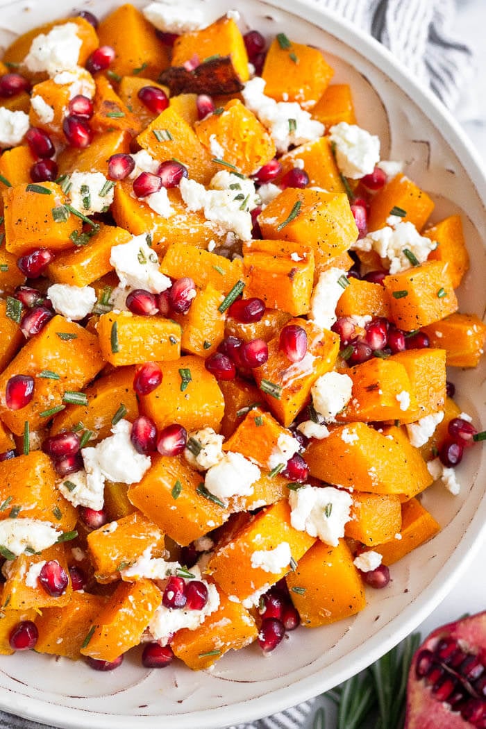 Overhead image of roasted squash in a bowl with pomegranate and goat cheese mixed in