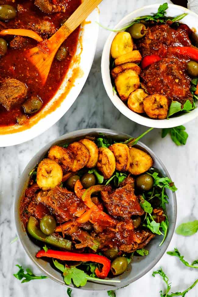 Ropa vieja served up in bowls with greens and fried plantains. 