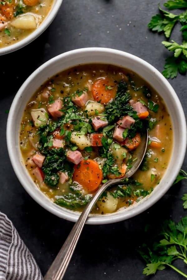 Ham and potato soup in a bowl with carrots and parsley