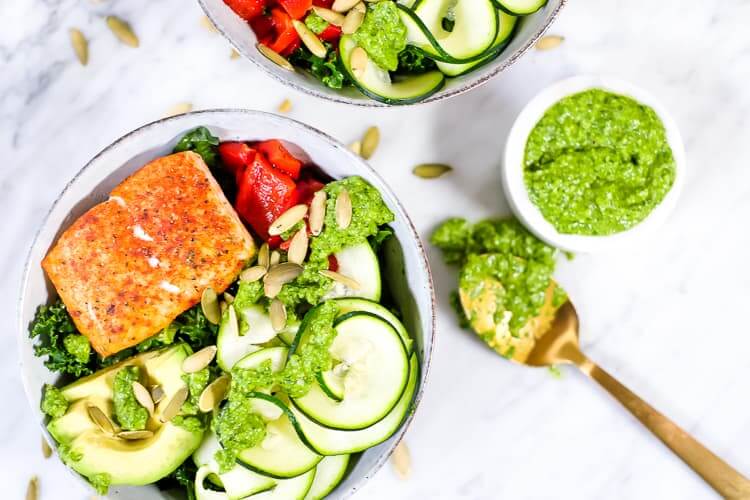 Salmon pesto kale veggie bowl with pesto sauce and pumpkin seeds