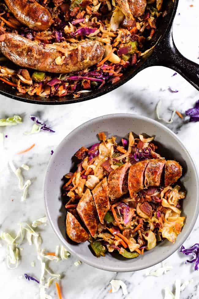 Sausage and cabbage skillet served in a bowl with a sliced up sausage. 