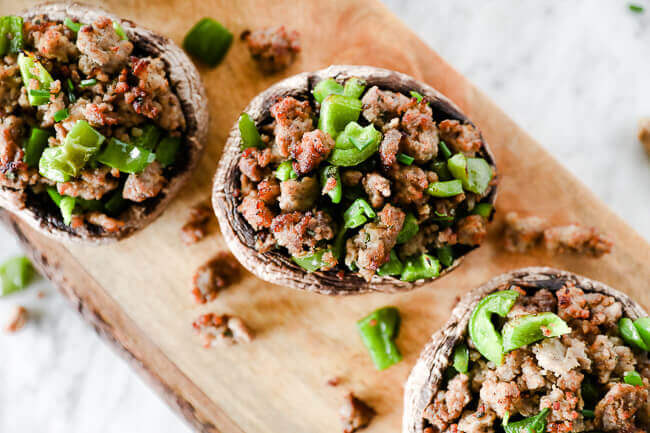 sausage stuffed mushrooms with chopped green peppers on board horizontal image