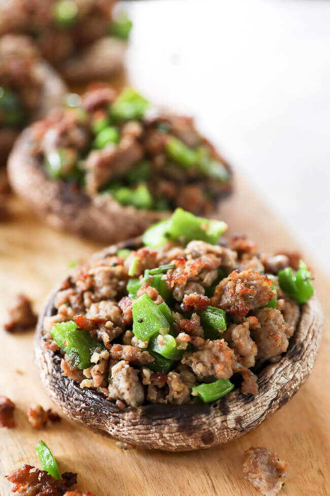 sausage stuffed mushrooms with chopped green peppers on board angle close up image