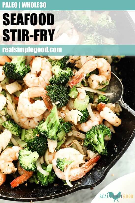 Close up image of seafood stir-fry served in cast iron skillet with shrimp, white fish, broccoli, celery and onion and cajun seasoning. Text on top of image for pinterest. 