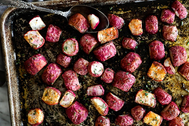 Roasted radishes on sheet pan with spoon horizontal image