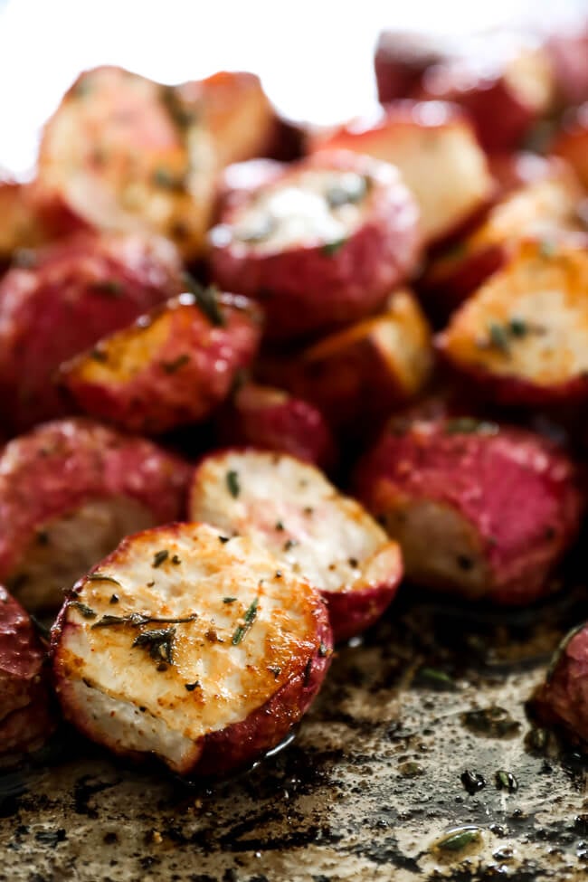 Roasted radishes piled up on sheet pan close up at an angle vertical image