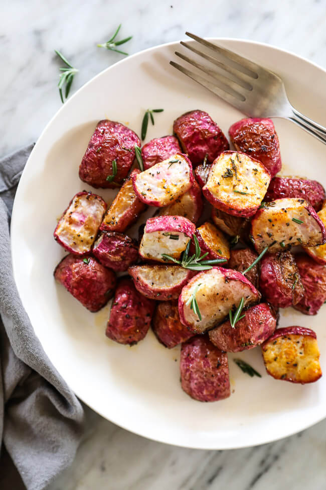 Roasted radishes on a plate with fork topped with rosemary vertical image