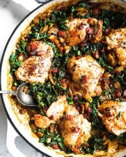 Overhead image of skillet chicken thighs in mustard sauce with kale and bacon
