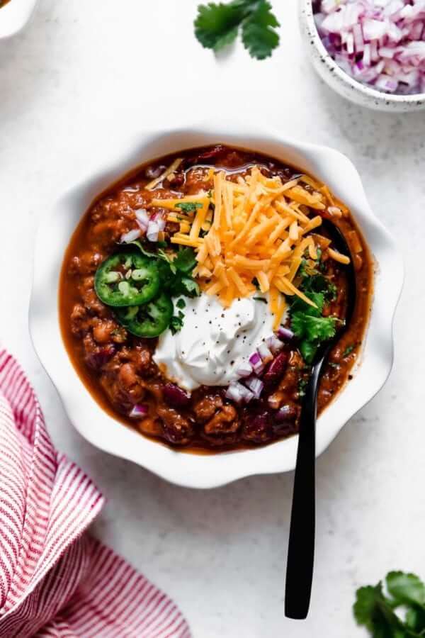 Overhead shot of chili with cheese, jalapeno and sour cream toppings