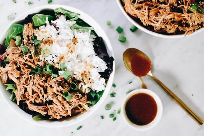 Slow cooker teriyaki chicken in a bowl with white rice, greens and teriyaki sauce