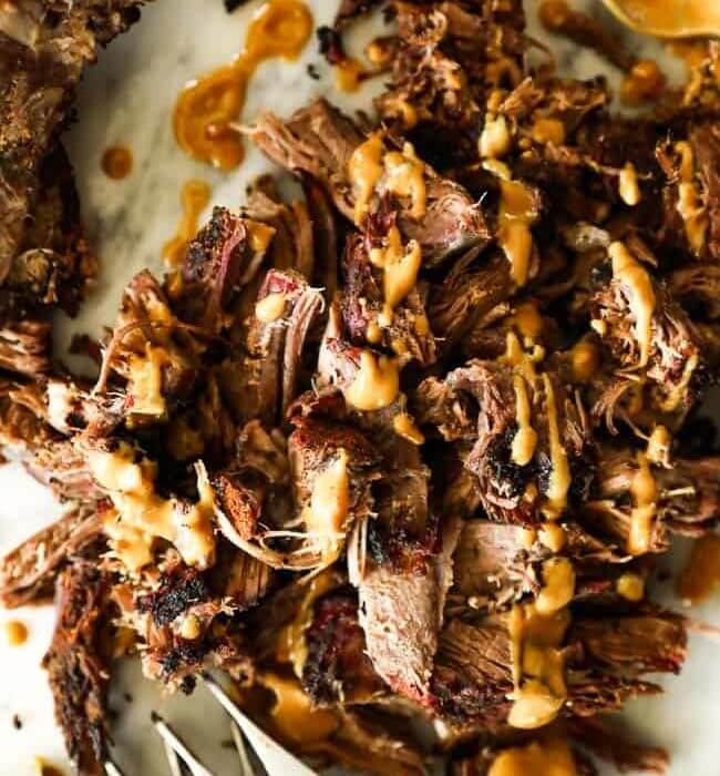 Pulled smoked chuck roast close up at angle with mustard sauce over top
