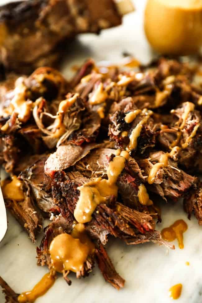 Pulled smoked chuck roast close up at angle with mustard sauce over top 