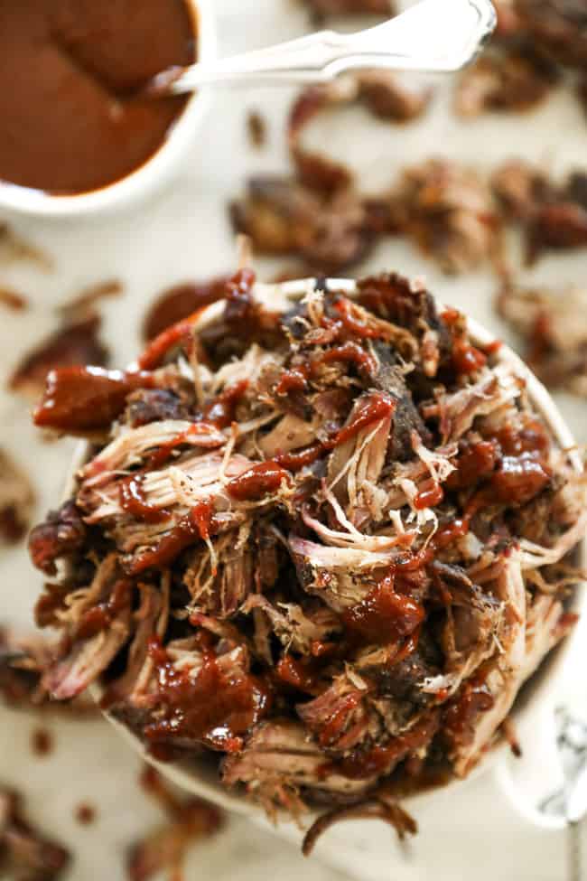 Smoked pork shoulder pieces in a bowl with sauce over the top overhead shot