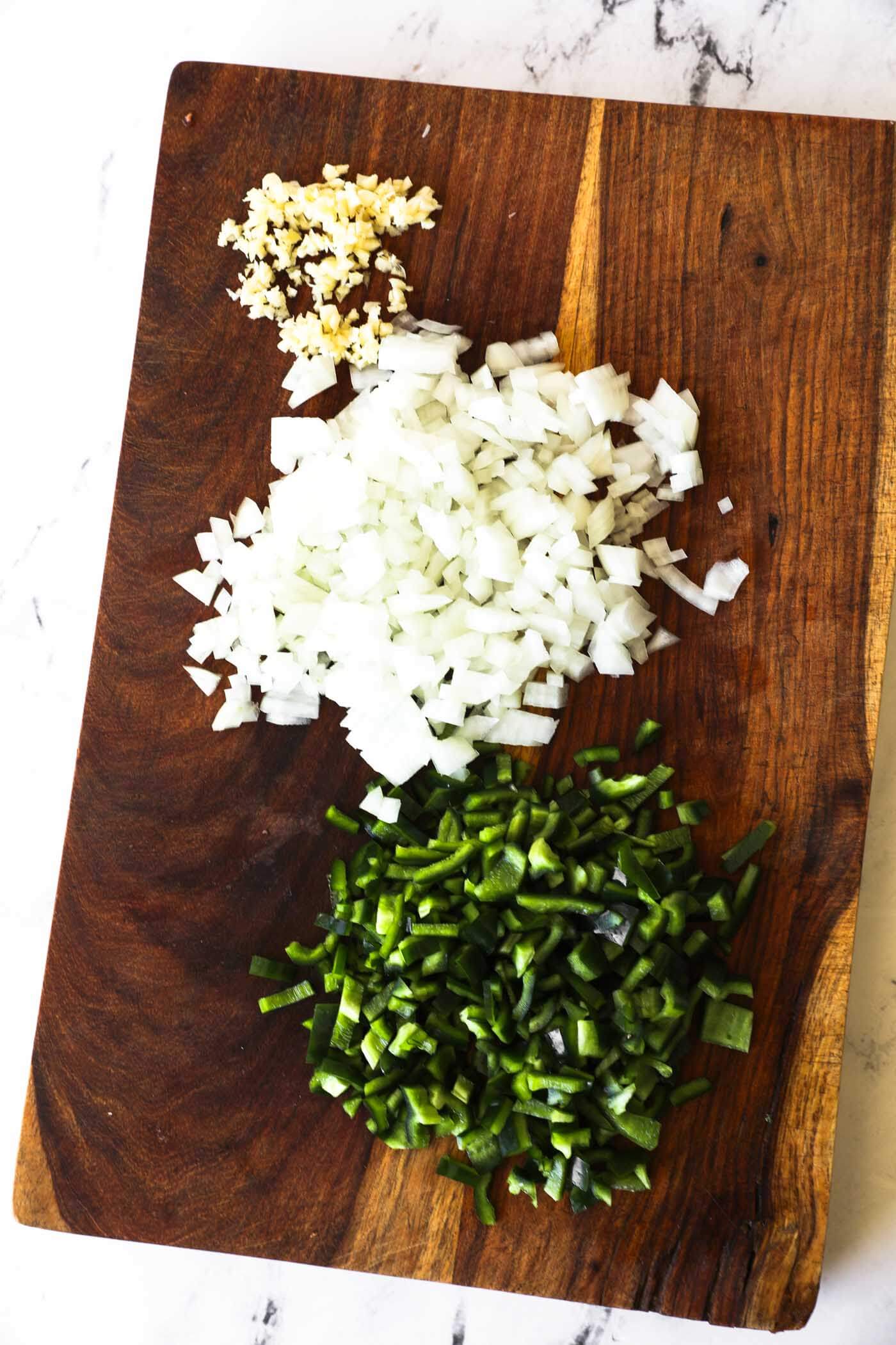 Diced onion, poblano pepper and garlic on a cutting board.