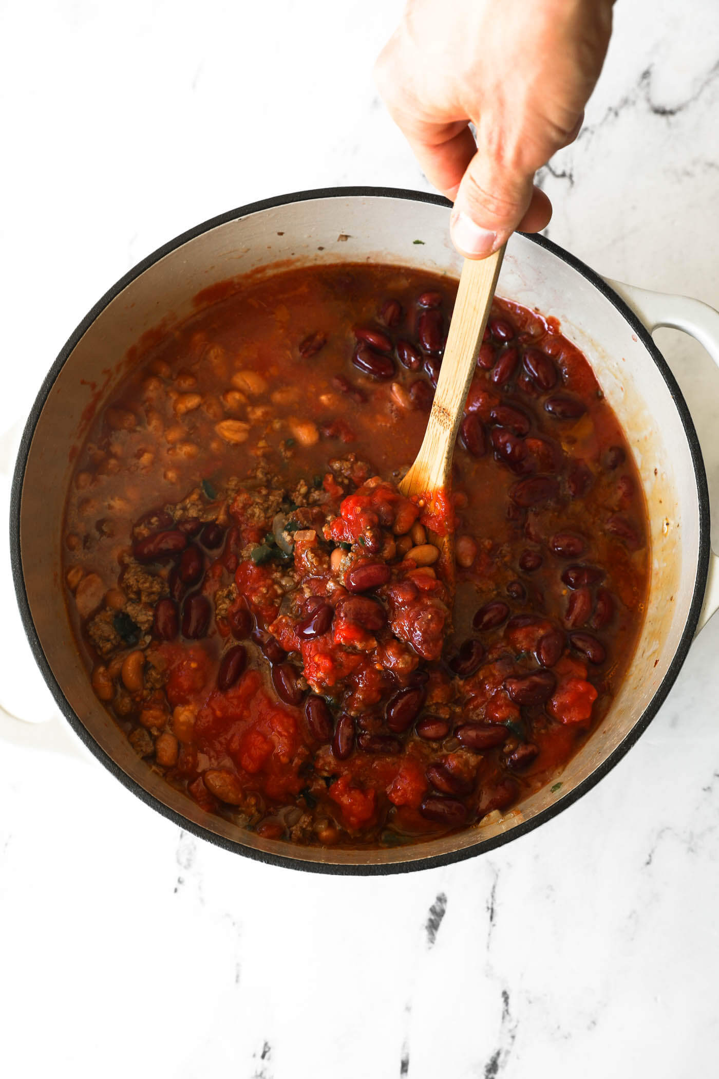 Stirring all of the chili ingredients together in a dutch oven before covering to simmer on the stove. 