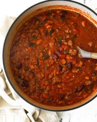 Dutch oven full of chili with a serving spoon dug into the pot.