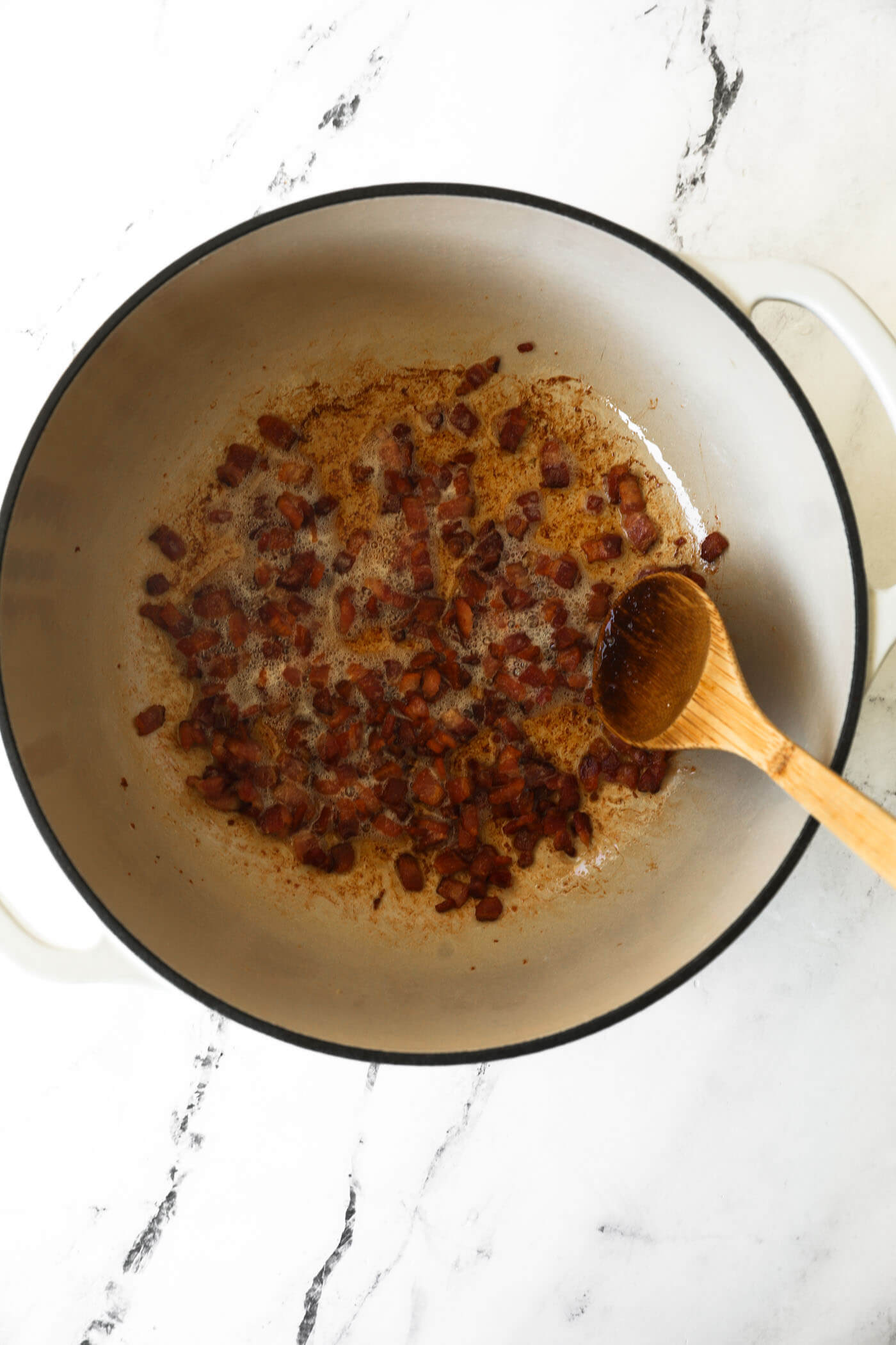 Diced bacon cooking in a dutch oven.