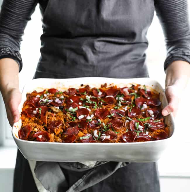 Holding casserole dish as if about to set spaghetti pizza casserole on the table. 