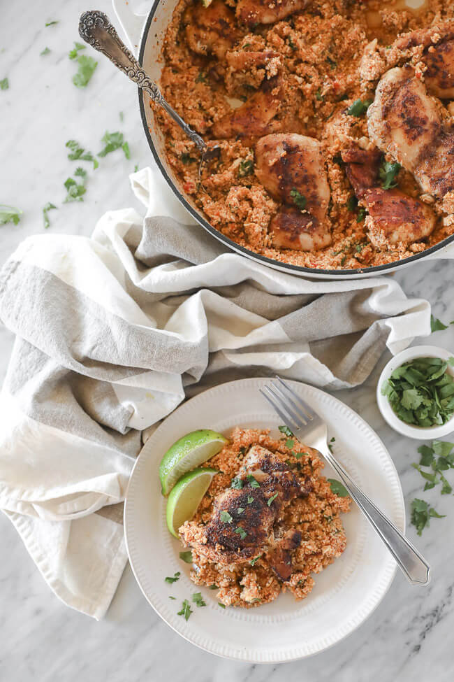 Chicken thigh and cauliflower rice on a plate with fork topped with cilantro overhead vertical shot