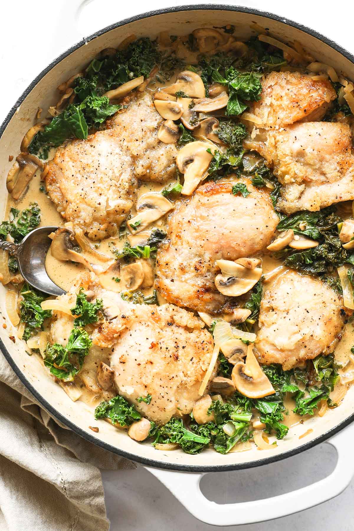 Overhead shot of creamy mushroom chicken in a pan with creamy dairy free sauce and kale