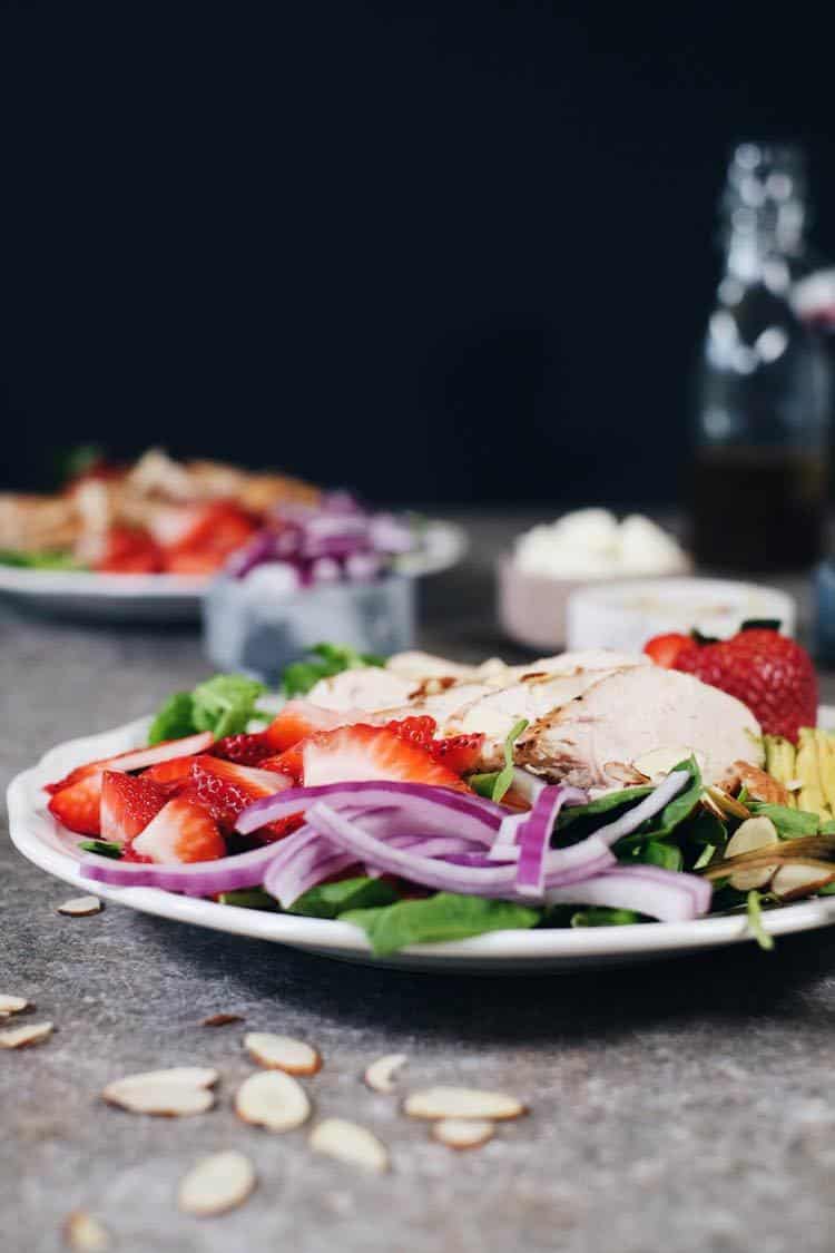 In just 30 minutes this Paleo + Whole30 savory and sweet strawberry chicken salad will be on the table! It's full of flavor and super easy to make! Simple chicken pairs perfectly with arugula, spinach, strawberries, avocado, red onion, sliced almonds and an easy balsamic dressing. Paleo + Whole30 | realsimplegood.com