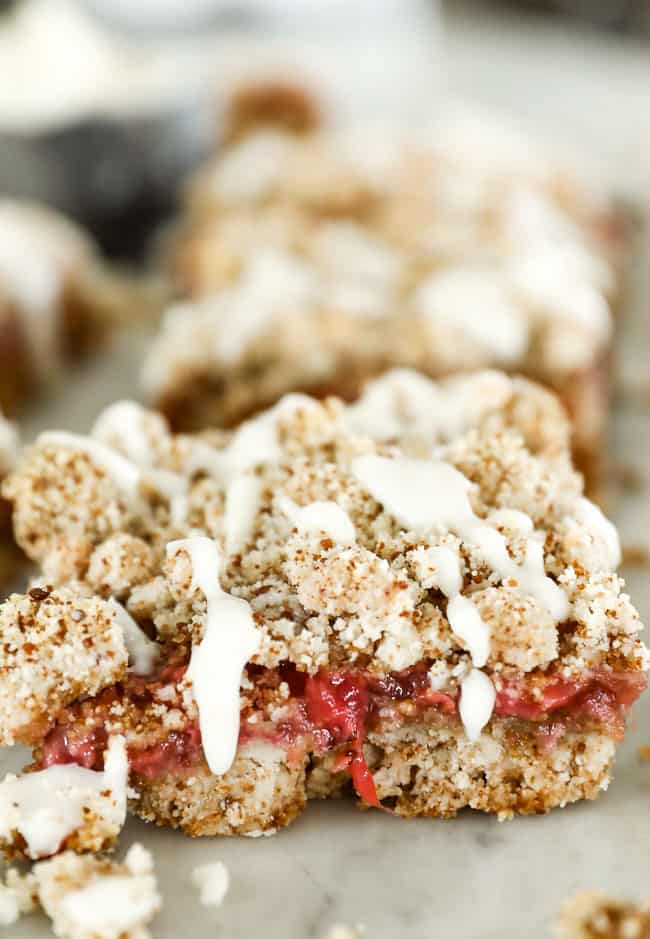 Close up image of strawberry crumble bar with drizzle of coconut butter dripping down the side. 