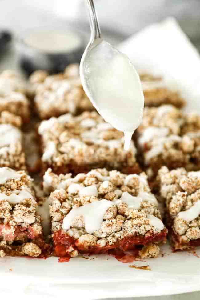 Image of drizzling coconut butter on top of strawberry crumble bars. 