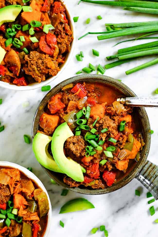 Paleo + Whole30 sweet potato chili in bowls with chopped green onion and avocado slices. 