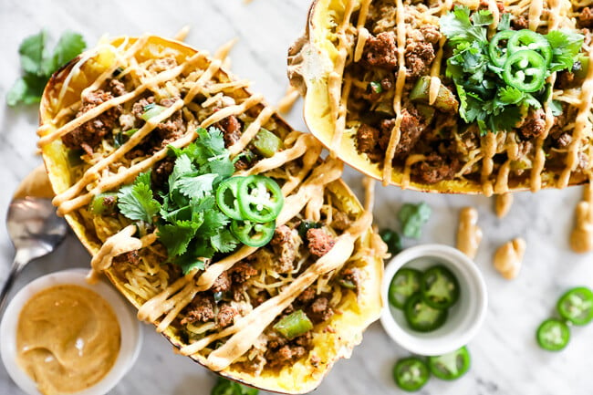 Taco stuffed spaghetti squash with sauce drizzled on top horizontal image