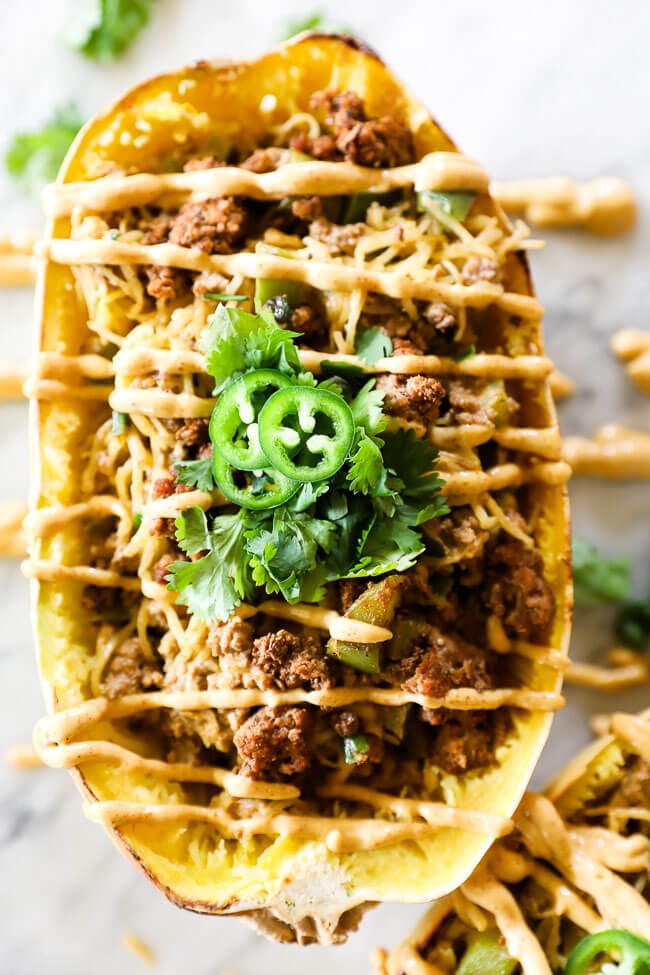 Taco stuffed spaghetti squash with sauce drizzled on top close up image of vertical squash