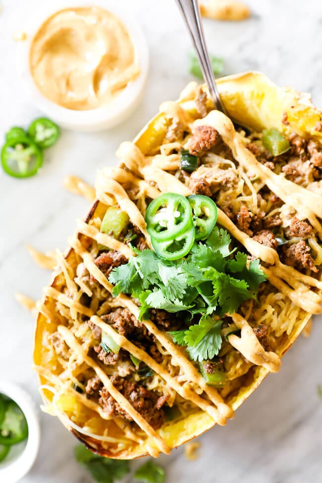 Taco stuffed spaghetti squash with sauce drizzled on top close up image of single squash