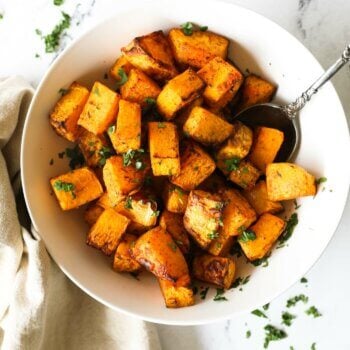 Cooked air fryer butternut squash cubes in a bowl with spoon coming out.