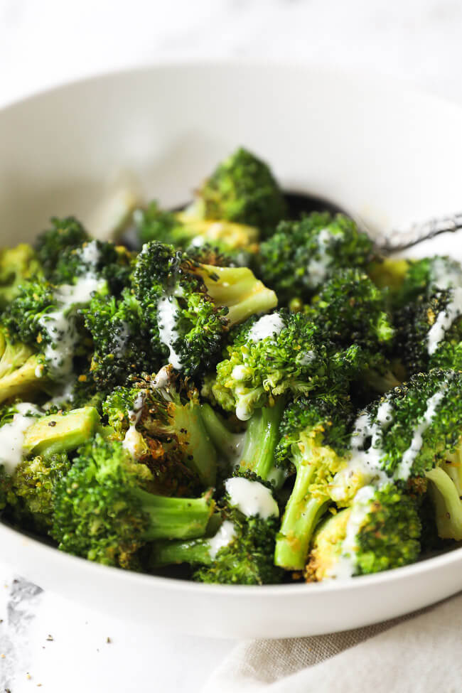 Angled close up of bowl of air fryer broccoli with ranch drizzled on top. 