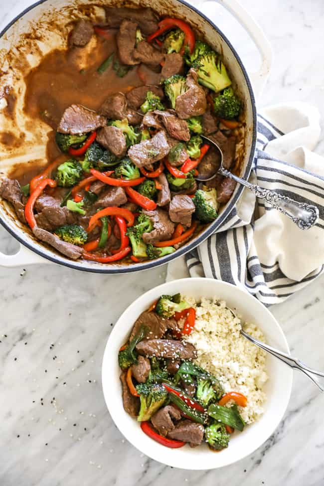 Overhead shot of teriyaki beef recipe in pan with spoon. Teriyaki beef in bowl with cauliflower rice and spoon.