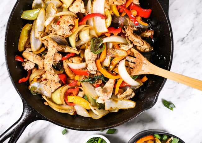 Thai basil chicken in a cast iron skillet with a serving spoon. 