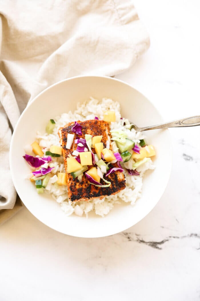 Overhead shot of a bowl with rice, one piece of blackened mahi mahi and a mango slaw on top.