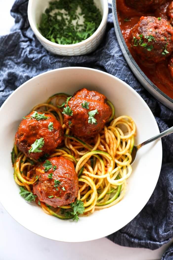 Overhead image of a bowl of zoodles with three big meatballs in marinara sauce.