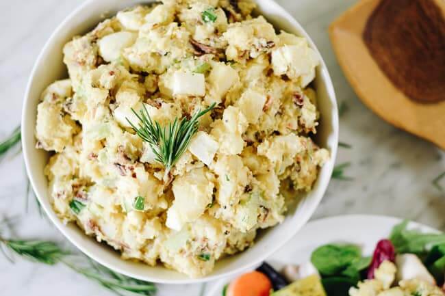 The best potato salad with bacon in a bowl with rosemary