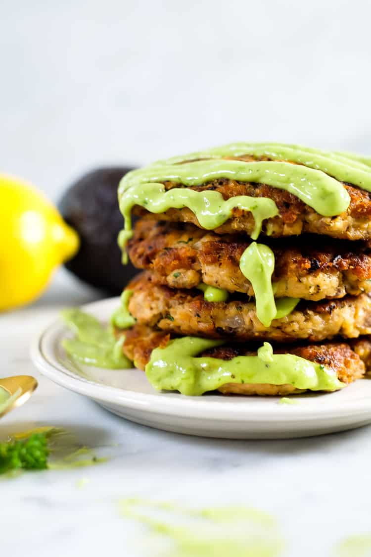 The best salmon patties stack with green sauce drizzle cascading down. 