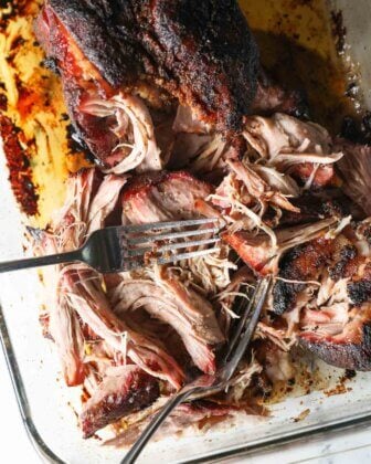 Close up of shredded pork with the two forks still in the pan.