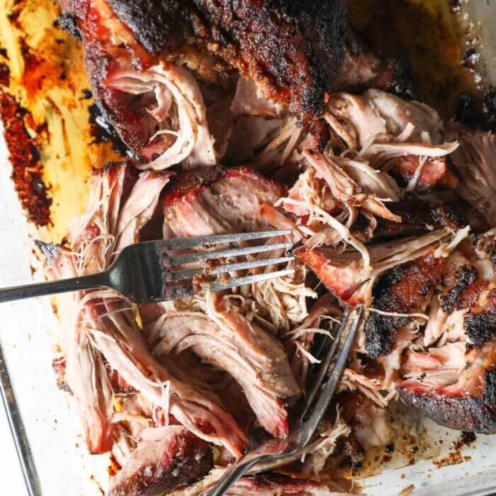 Close up of shredded pork with the two forks still in the pan.