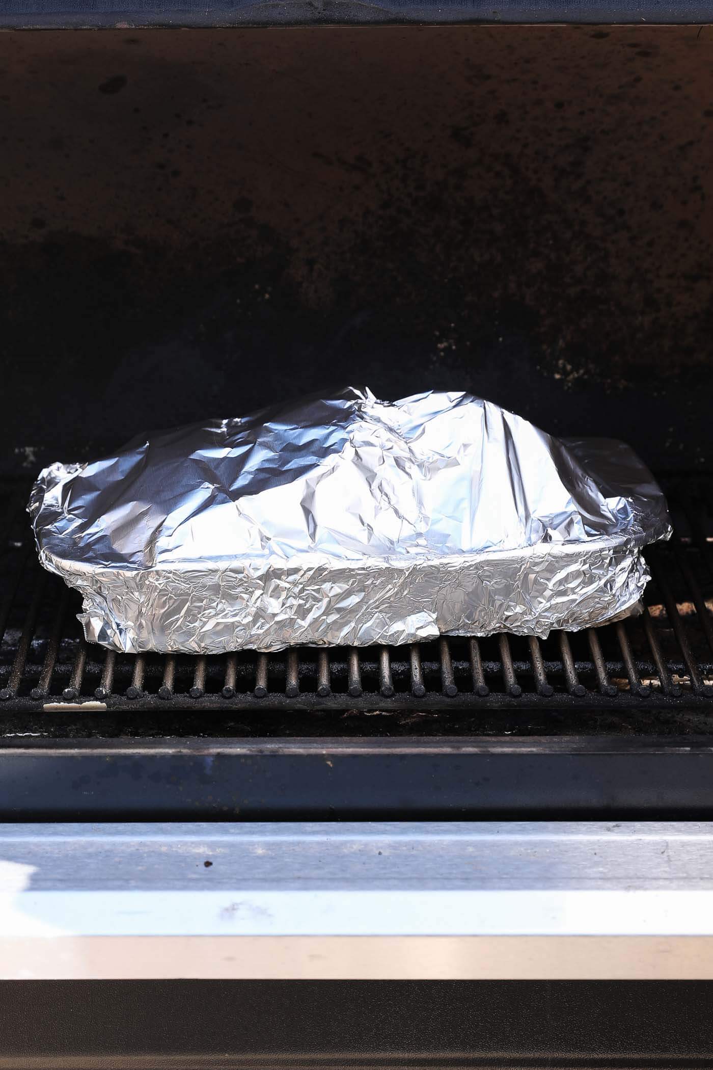 A pork roast with pats of butter on top, tented with foil and put back on the traeger grill.