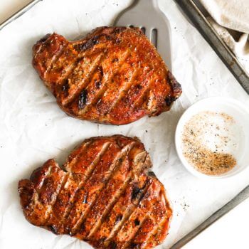 Overhead shot of traeger smoked pork chops on a pan with seasoning and spatula under one chop