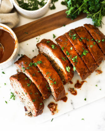 Overhead image of sliced smoked meatloaf with glaze and chopped parsley topping
