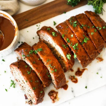 Overhead image of sliced smoked meatloaf with glaze and chopped parsley topping