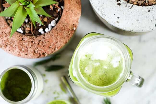 Iced matcha latte in a mason jar mug with succulents. 