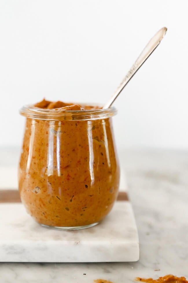 Whole30 roasted red pepper sauce in jar with spoon coming out straight on shot