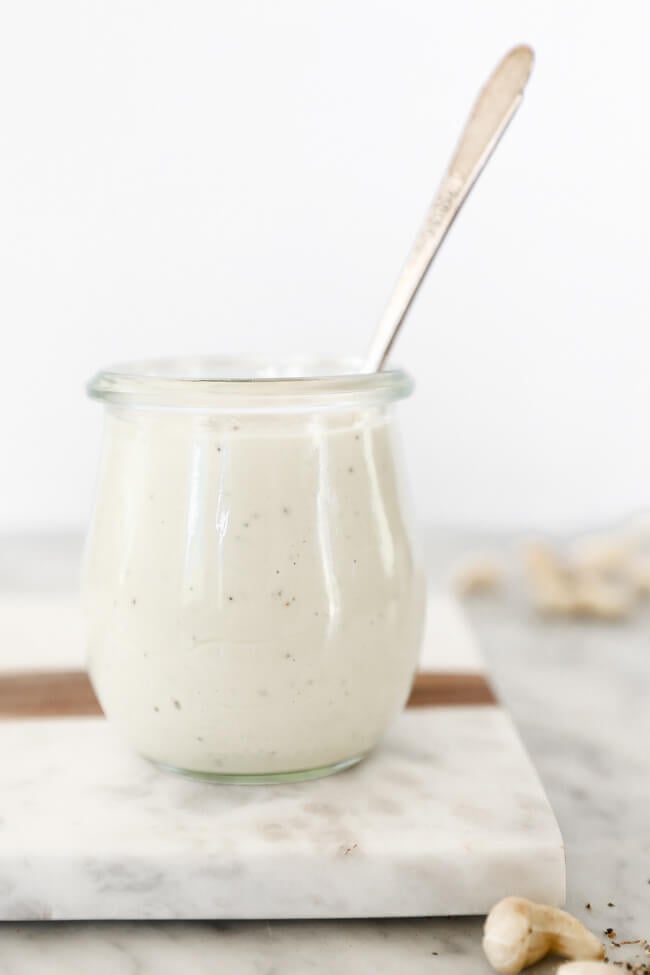 Whole30 creamy garlic sauce in jar with spoon coming out straight on shot