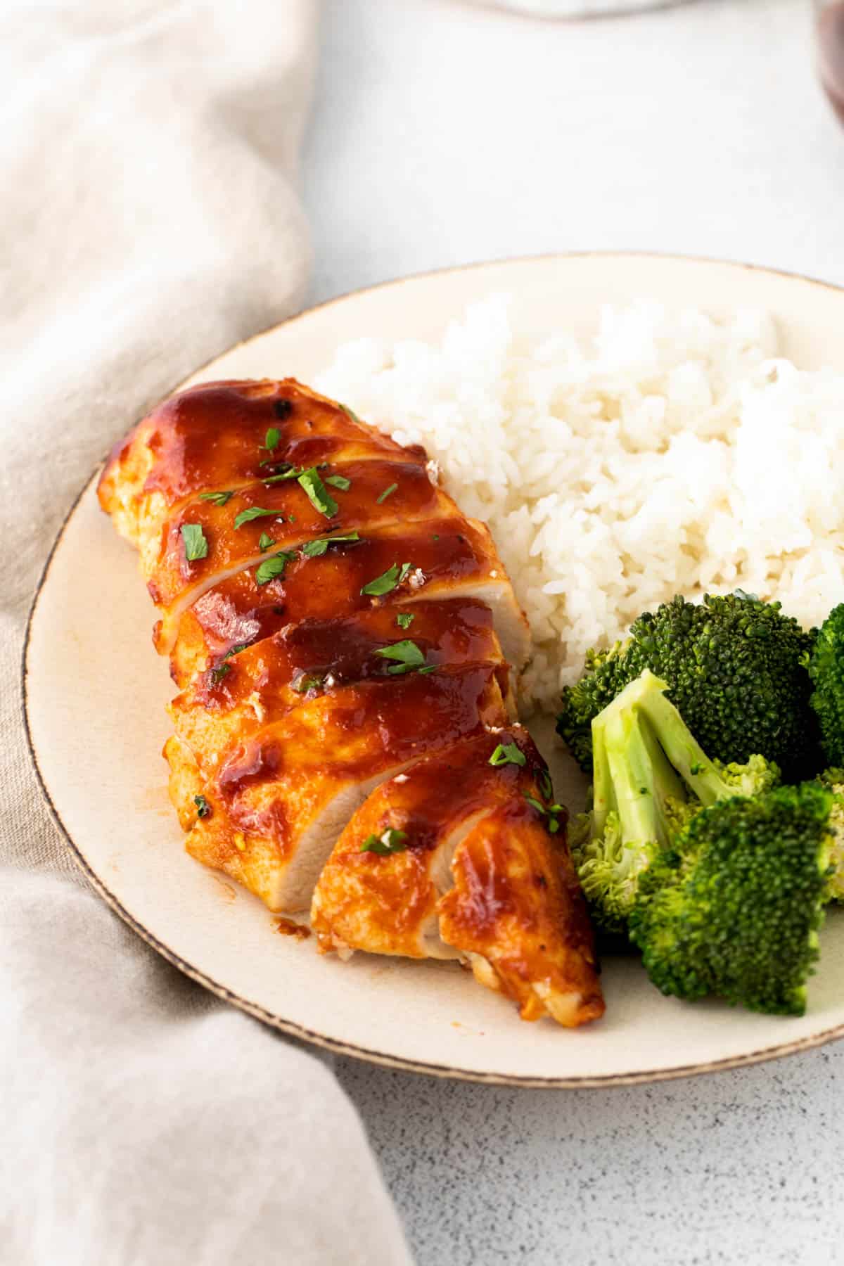 Angle image of sliced chicken breast with BBQ sauce with rice and broccoli